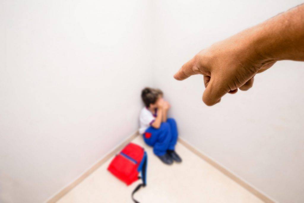 Adult hand pointing at child in school uniform crying, concept of child abuse or bullying.