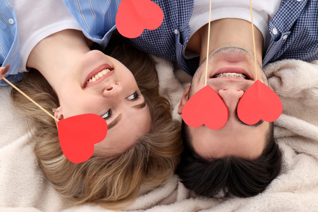 Cute and happy couple with hearts lying